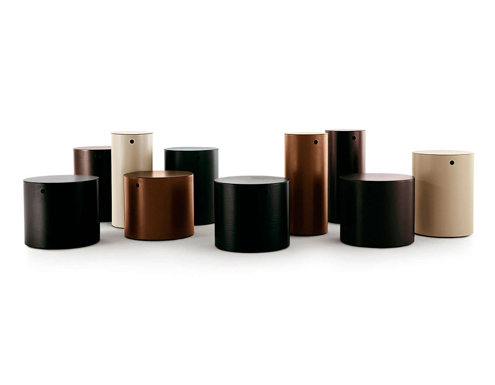 line of tables in the shape of cylinders of different sizes and colors such as black and white coffee made of brass and leather
