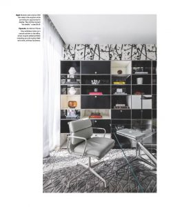 Sleek home office with a glass desk, modern chair, and black shelving accented by artistic wallpaper and geometric decor.