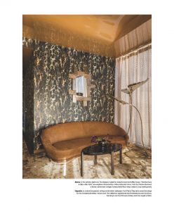 This image presents a luxurious seating area with a curved velvet sofa, a round black coffee table, and an accent wall featuring a nature-inspired pattern in gold tones, creating a warm and sophisticated ambiance