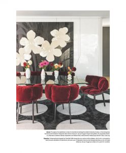 A stylish dining room featuring plush red velvet chairs, a glass dining table, and a bold floral wall art piece against a sleek white backdrop.