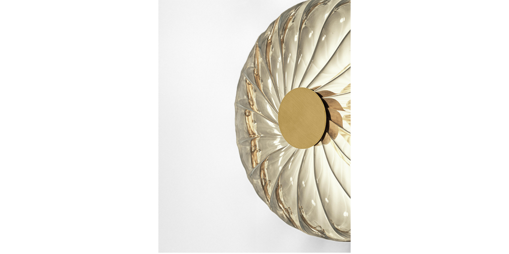 wall lamp made of light colored glass and brass on a white background