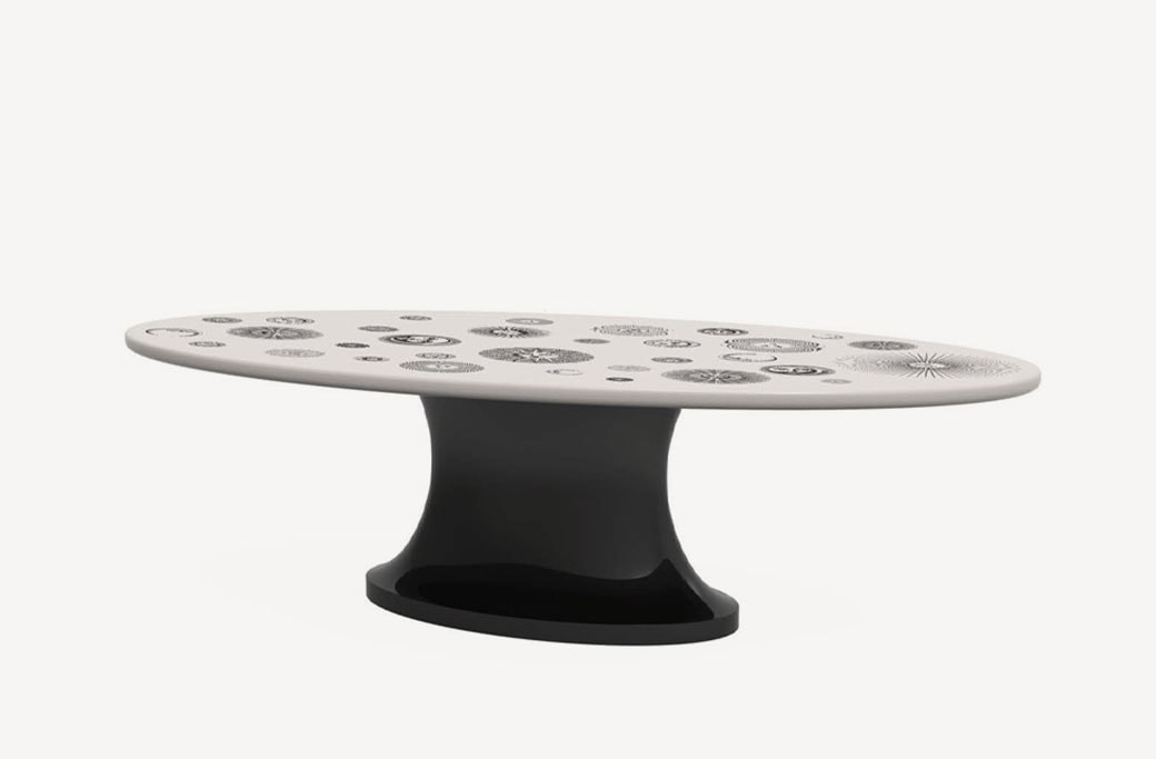 A black-and-white pedestal serving plate with intricate surrealist illustrations, blending functionality with artistic elegance