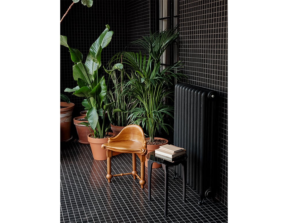 side table with black glass top and wooden base of the same tone in a living room