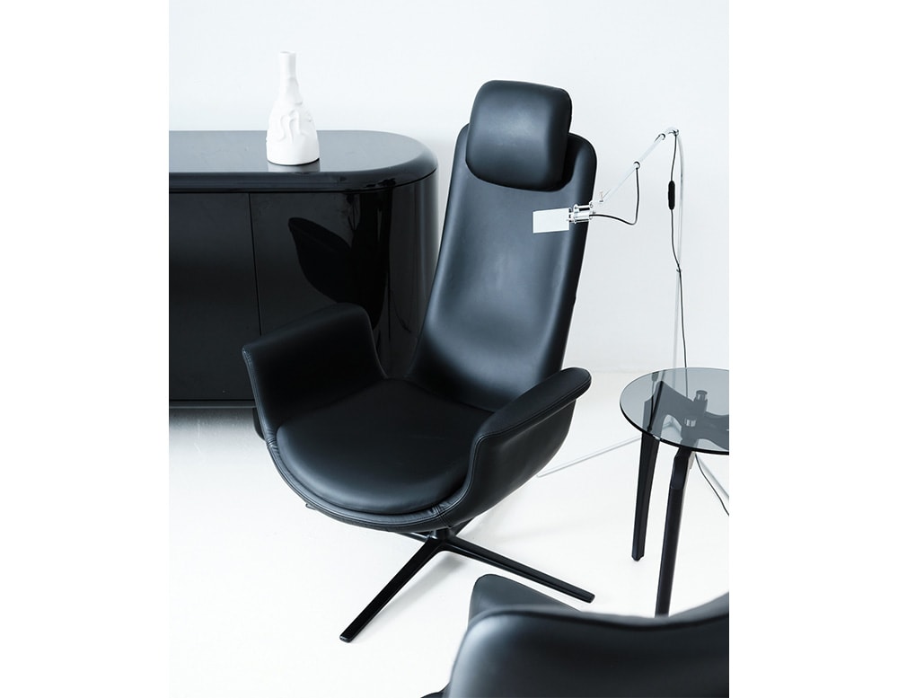 armchair made of aluminum and upholstered in black leather throughout its structure in a living room