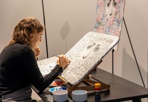 An artist meticulously hand-paints an intricate Fornasetti-inspired design, bringing timeless craftsmanship to life