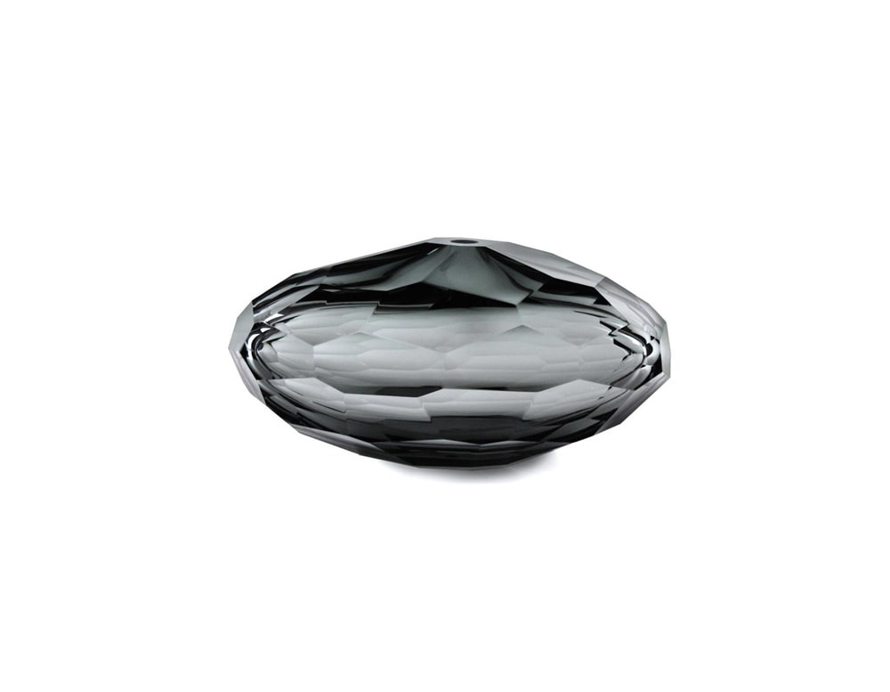 transparent black glass sculpture with an oval shape and pentagon-shaped finishes in a white background
