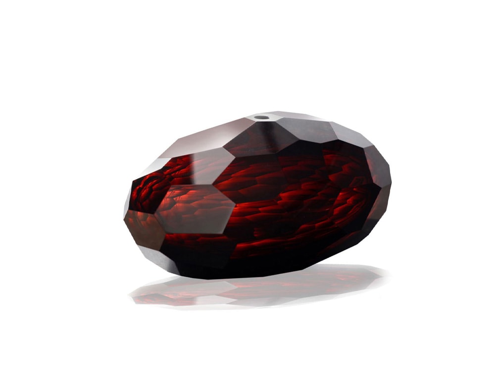 small glass sculpture with pentagon-shaped finishes in a ruby red tone in a white background