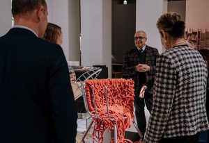A group admires an intricate red chair design at an Edra event, where innovation and artistry come together in contemporary furniture
