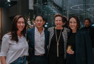 A group of elegantly dressed individuals enjoying an upscale event in a sophisticated showroom with modern design and ambient lighting