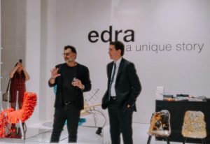 Two individuals engaged in a discussion at an Edra event, surrounded by avant-garde furniture pieces in a modern exhibition space