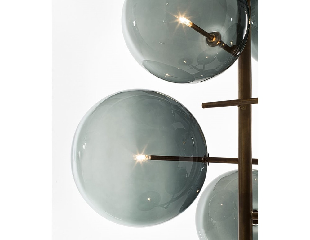 2 of the 7 clear gray blown glass spheres of a floor lamp with adjustable LED light on a white background.