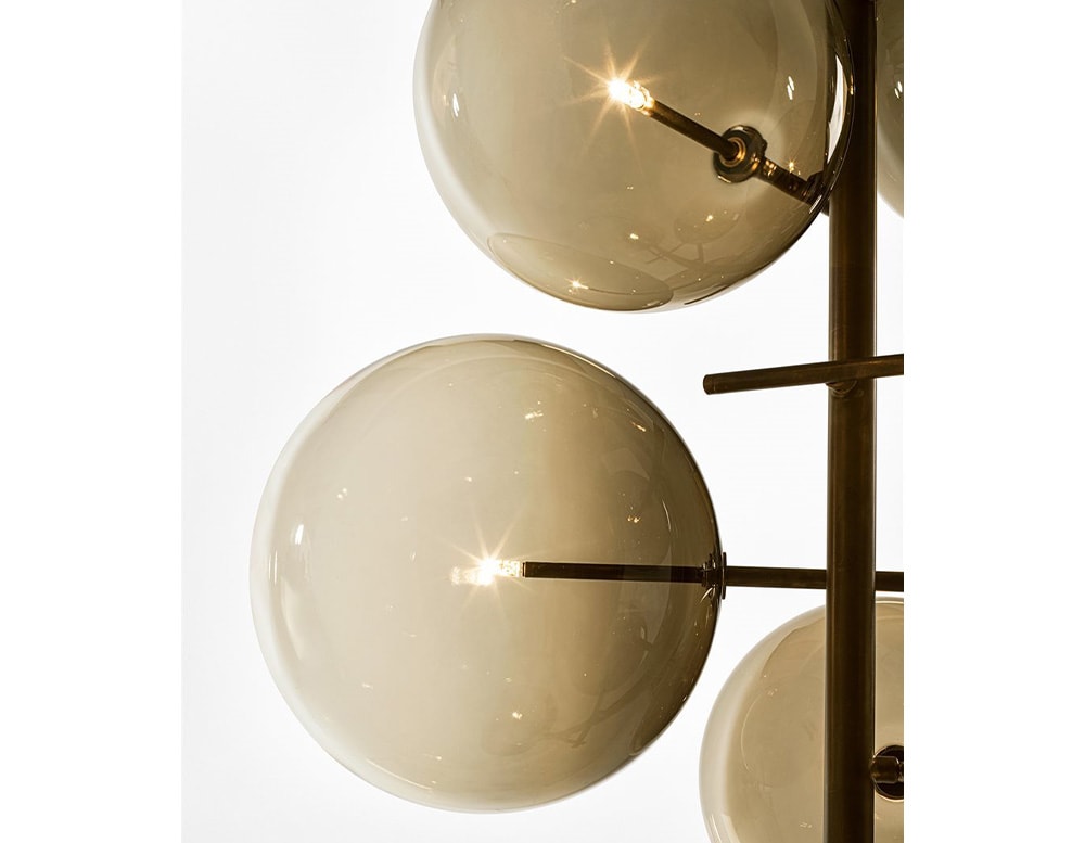 2 of the 7 clear yellow blown glass spheres of a floor lamp with adjustable LED light on a white background.