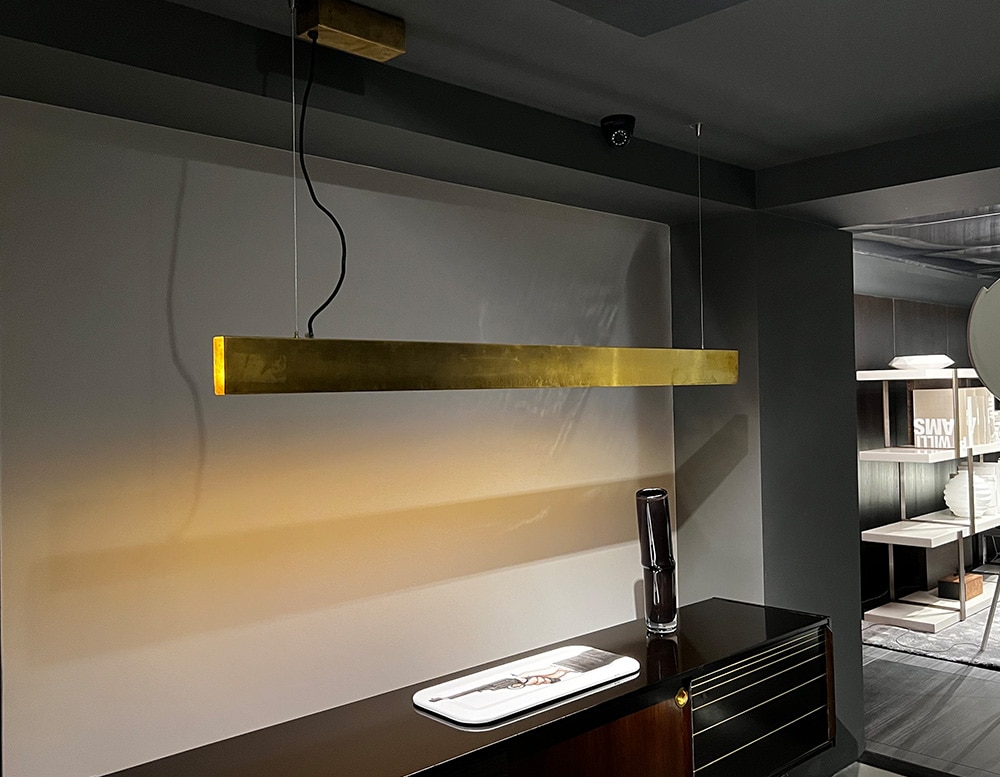 Side view of a LED suspension lamp made with a golden antiqued satin brass structure in a room