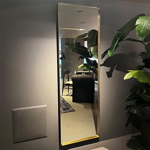 wall mirror made of glass and gold metal in a gray room.
