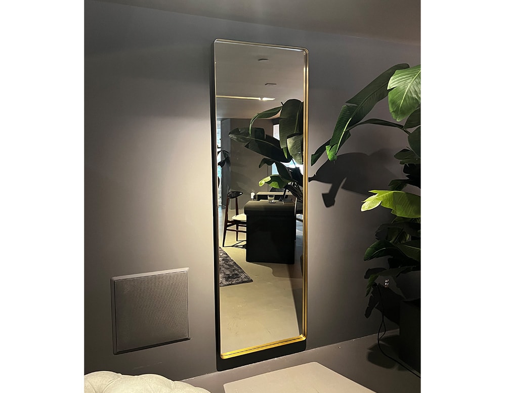 Baxter brand mirror made of glass and gold metal in a gray room.