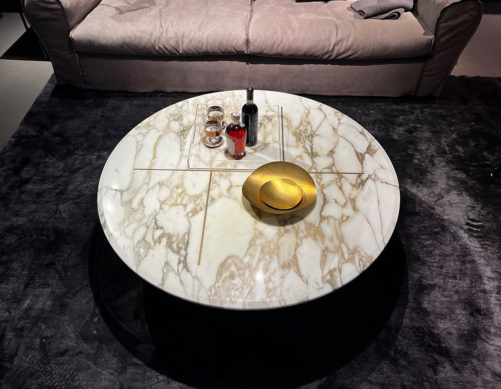 small oval table designed in metal and marble with a different shade of colors such as brown, gold and white in a living room.