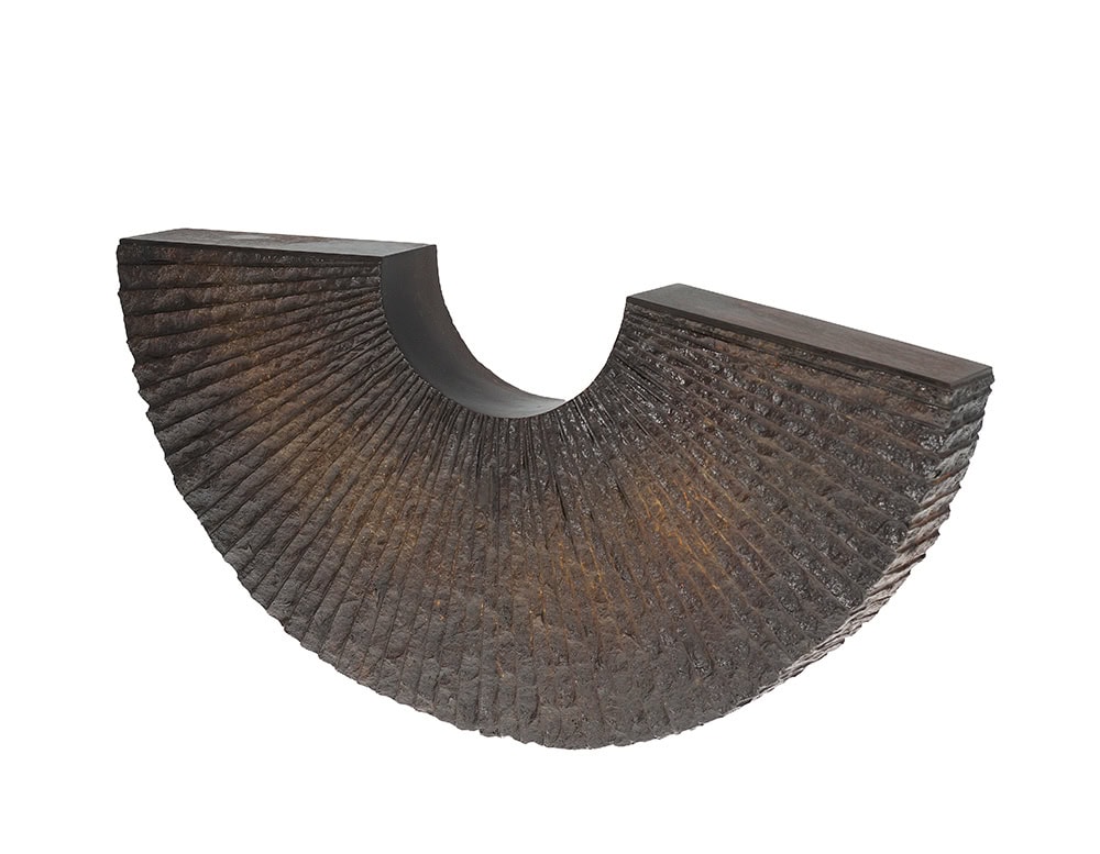 Sculptural piece with a half-circle silhouette carved in rich textured bronze. Its geometric balance and artisanal finish make it both a functional accent and a striking decorative object.