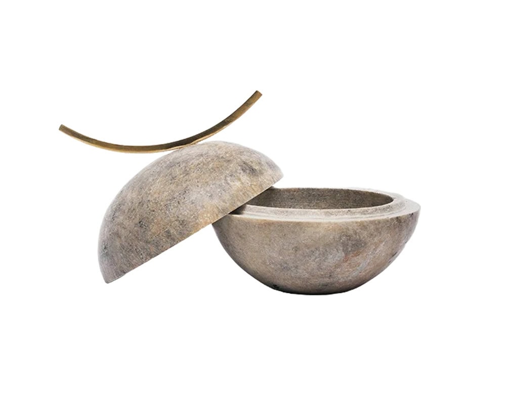 Stone accessory bowl with a sculptural half-sphere lid and a slim brass handle, combining natural textures with a refined, minimalist design.