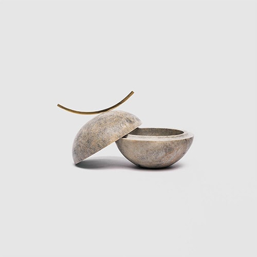 small soapstone vessels with different shades of gray and brass finishes, used to store small precious objects.