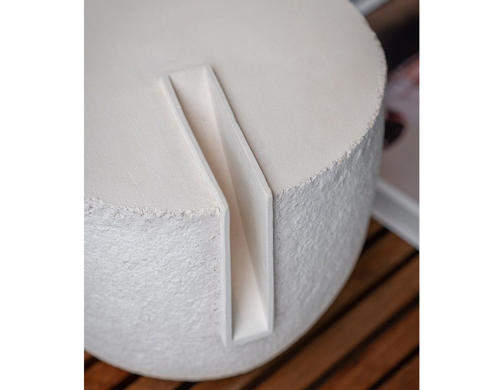 White ceramic sculpture with a small, narrow opening at the top.