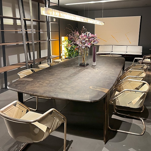 Dining table with walnut wood fusion top in a black micro-mosaic pattern, supported by slender bronze legs