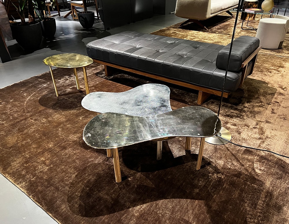 Sand-cast coffee tables in black brass finish with white details and gold-colored metal legs
