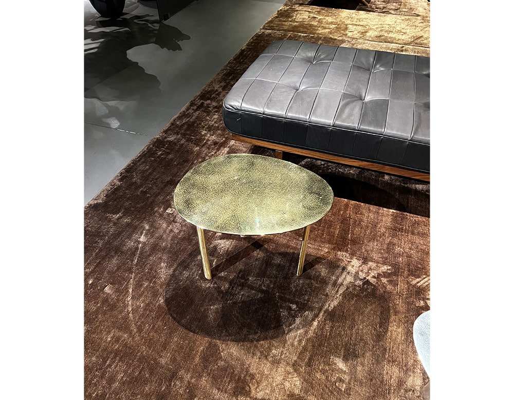 Sandcasting Brass finish coffee table in golden brass finish with white details and gold-colored metal legs in a room