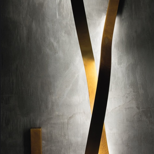 two ribbon-shaped wall lamps in bronce burnished brass finish in a white wall
