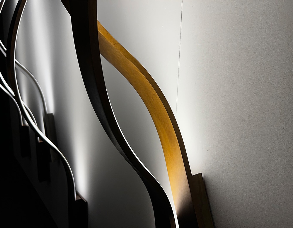 Two ribbon-shaped wall lamps in black and bronce burnished brass finish