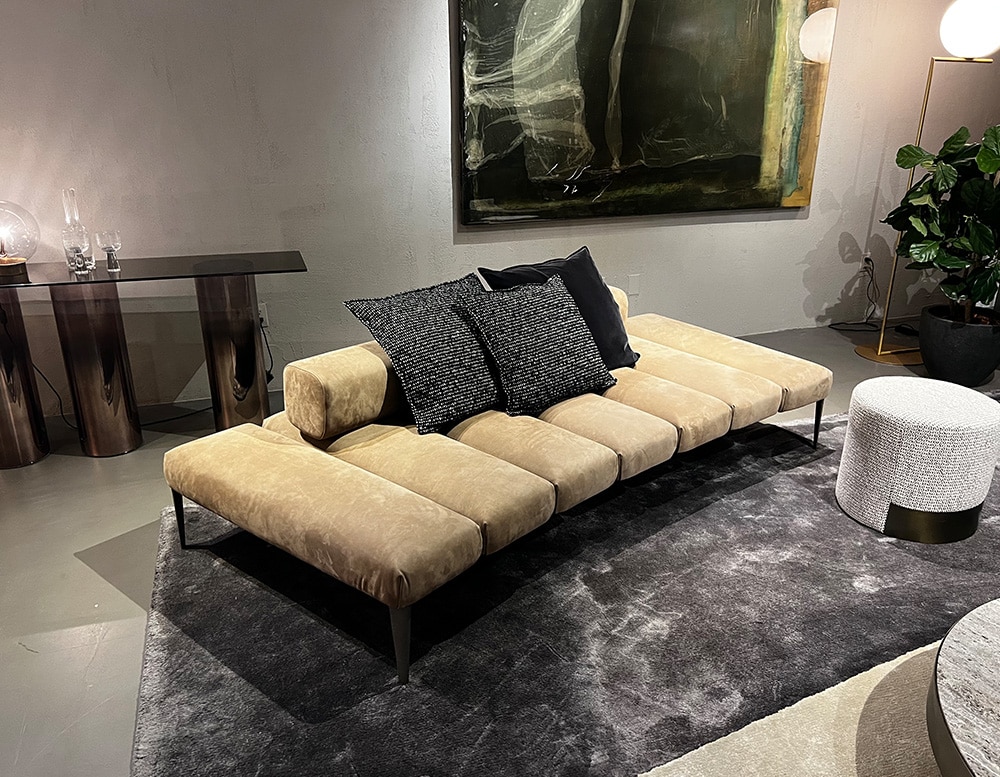 Sofa with backrest covered in beige leather with 7 divisions, thin black legs and black decorative cushions