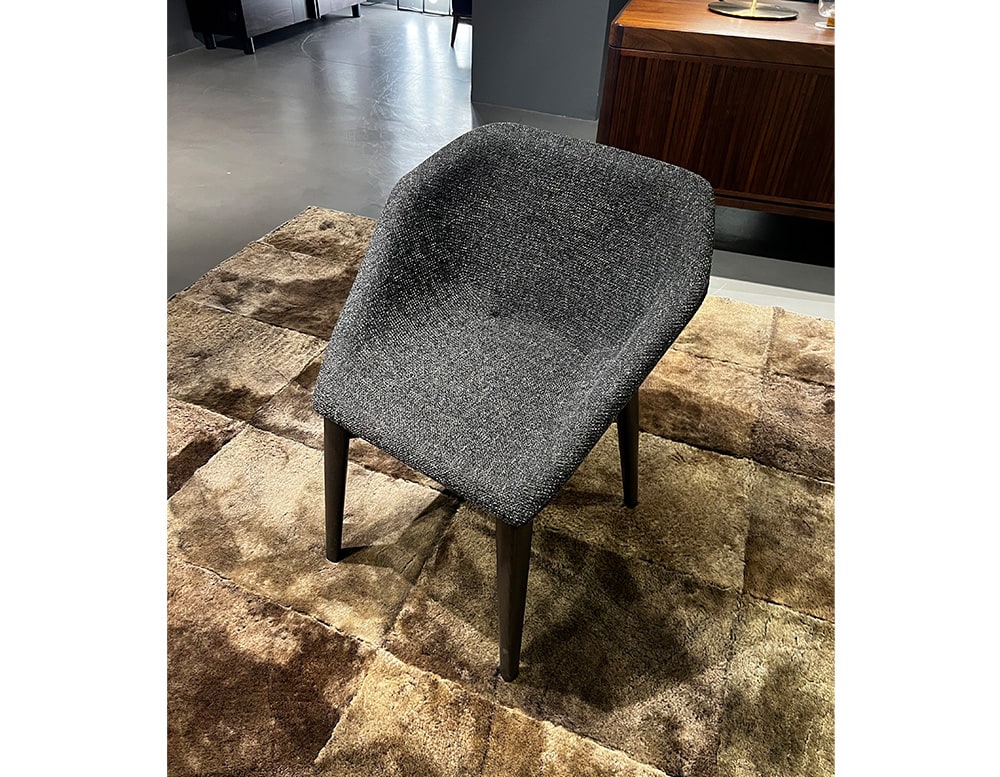 High quality handmade chair with gray and black fabric with a brown wooden base in a living room.