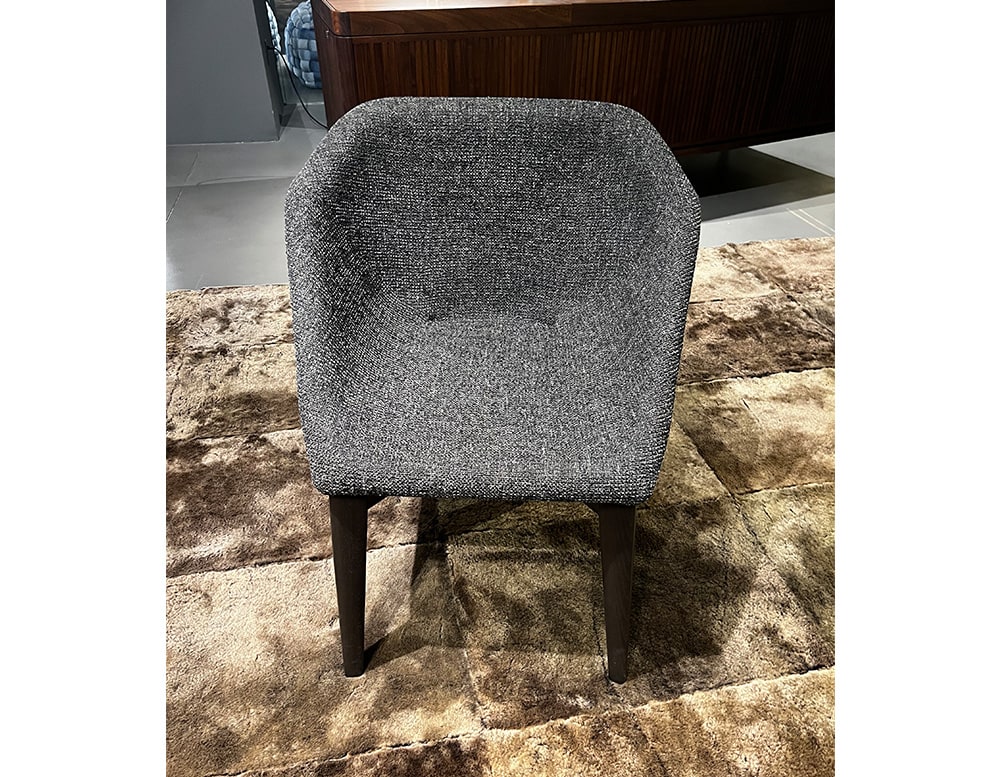 chair upholstered in gray and black fabric with shiny finishes on its upholstery in a living room.