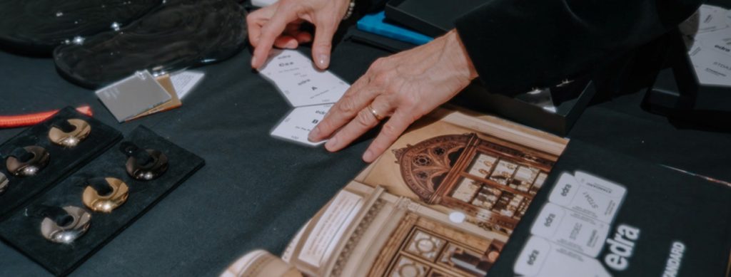 A close-up of hands engaging with architectural sketches, exploring intricate details of a classical building design at an Edra event