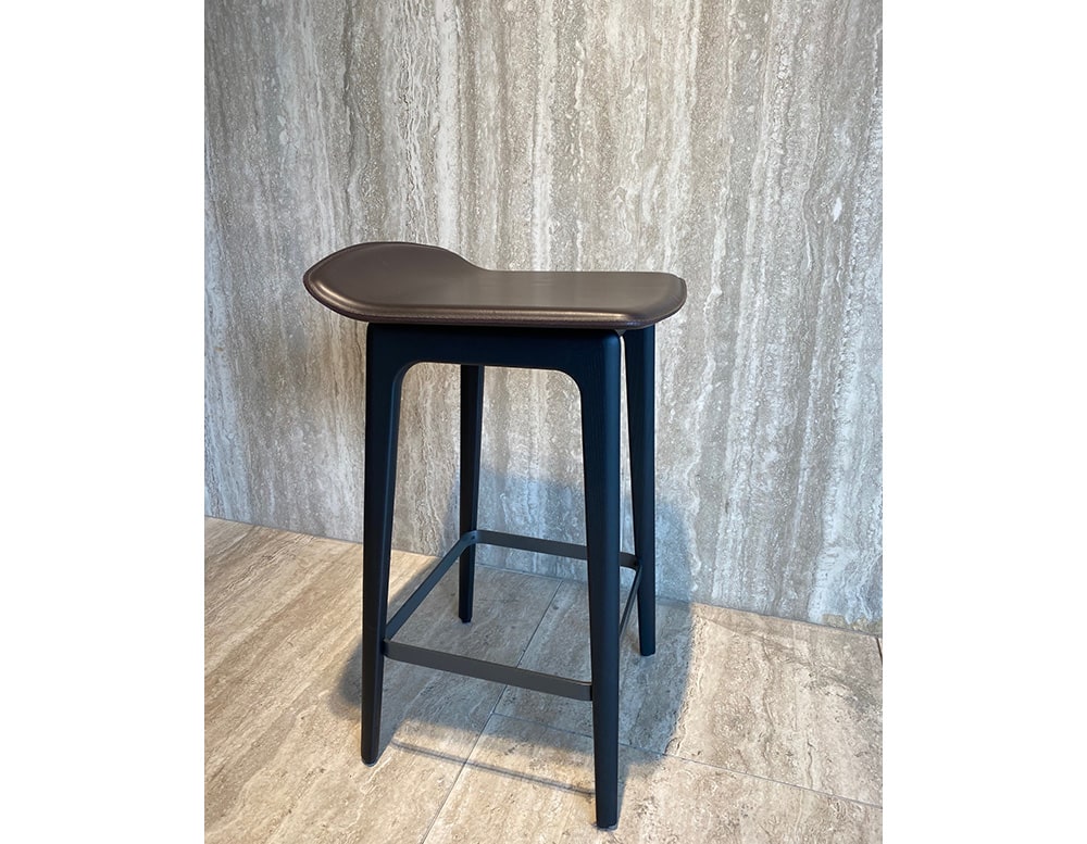 stool made from black lacquered ash wood and seat upholstered in brown leather in a living room