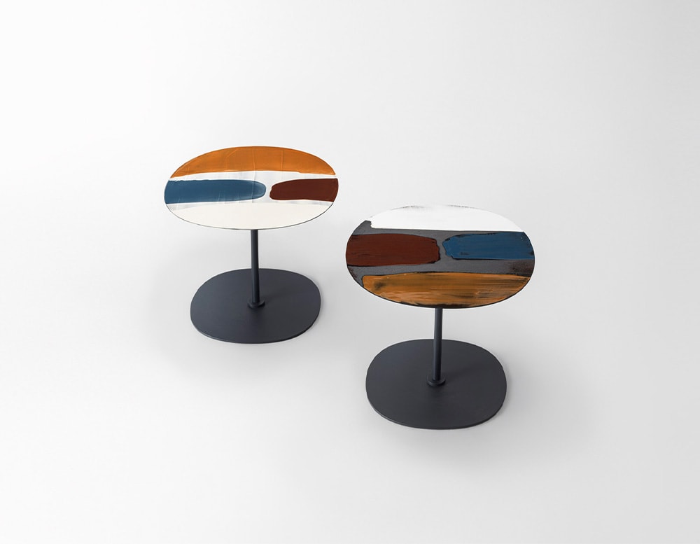 Two side tables with black base and tops in shades of red, white, black, blue and orange