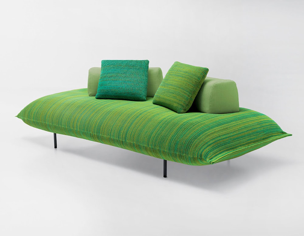 Platform composed of a single wide seat cushion in green tone with linear finishes and steel base on a white background