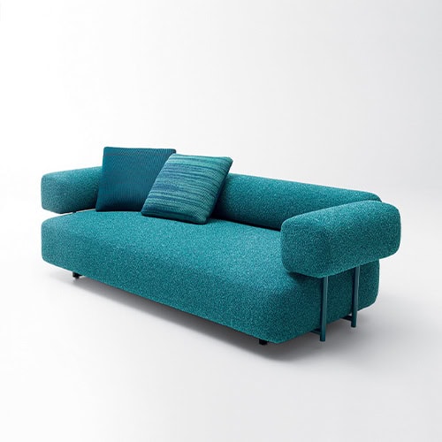 A modern Santorini Sofa in a vibrant teal hue, featuring plush cushions and a sleek, contemporary design