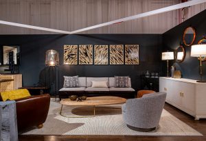 A sophisticated living room with a dark accent wall, modern furniture, warm lighting, and gold-toned abstract artwork creating an inviting ambiance