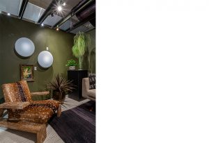 A modern interior with an earthy green accent wall, round wall lights, wooden furniture, and warm ambient lighting creating a cozy and stylish atmosphere