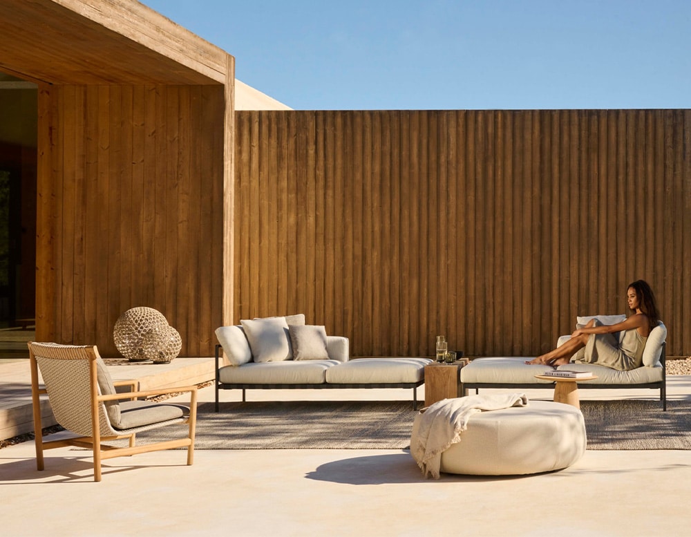 hand-woven chairs with their cushions in different shades of gray and white and brown wooden bases in an outside