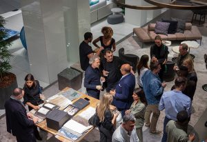 A lively gathering of elegantly dressed individuals engaging in conversation in a contemporary interior space with stylish furnishings