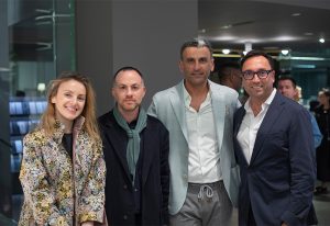 A group of four stylishly dressed individuals posing together in an upscale, modern setting with a sophisticated ambiance