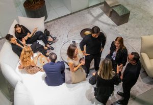 An overhead view of a social gathering where elegantly dressed individuals are engaged in conversations in a modern lounge setting