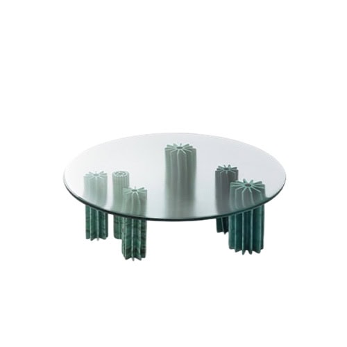 A striking side table featuring a round glass top supported by sculptural green column legs, creating a bold yet elegant statement for modern interiors.