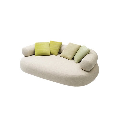 Curved ivory sofa with rounded armrests and soft contours, complemented by green accent pillows for a playful yet elegant look.