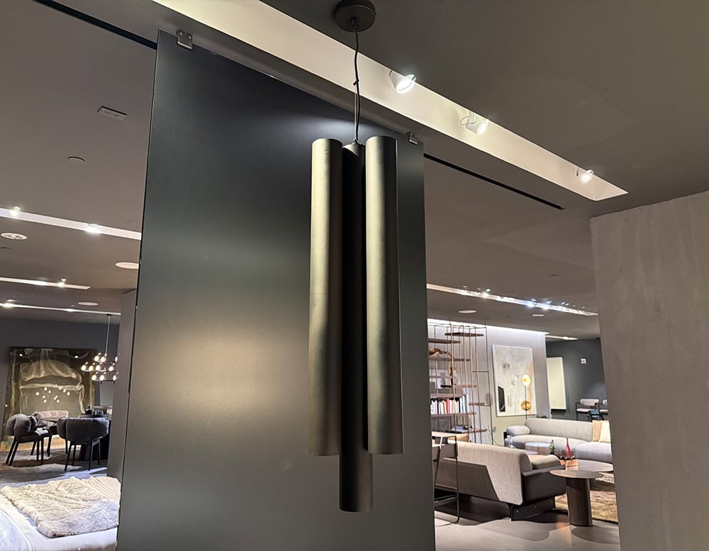 A sleek suspension light with elongated tubular shades in a metallic finish, offering a modern focal point and warm ambient illumination for contemporary interiors.