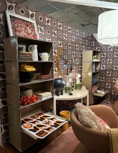 This vibrant corner blends retro patterns with modern design. Graphic wallpaper, modular shelving, and playful objects create a dynamic, curated space. Books, ceramics, and vintage art add layers of personality and texture.