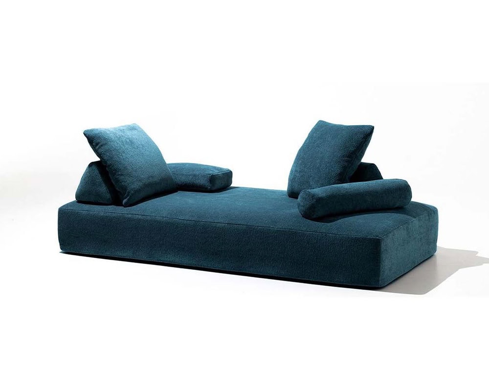 Blocky and low-profile in deep teal upholstery, this piece balances plush volume and crisp geometry. Twin tilted back cushions and cylindrical bolsters emphasize its lounge-ready, open-air silhouette.