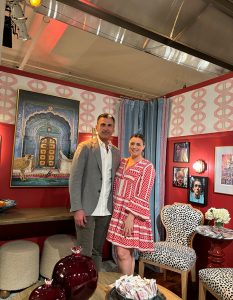 Guests stand in a vibrant showroom filled with bold patterns, curated art, and eclectic furnishings that blend traditional and modern elements.