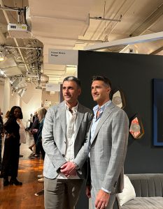 Guests stand side by side in a lively showroom aisle, surrounded by modern lighting, designer booths, and fellow attendees.